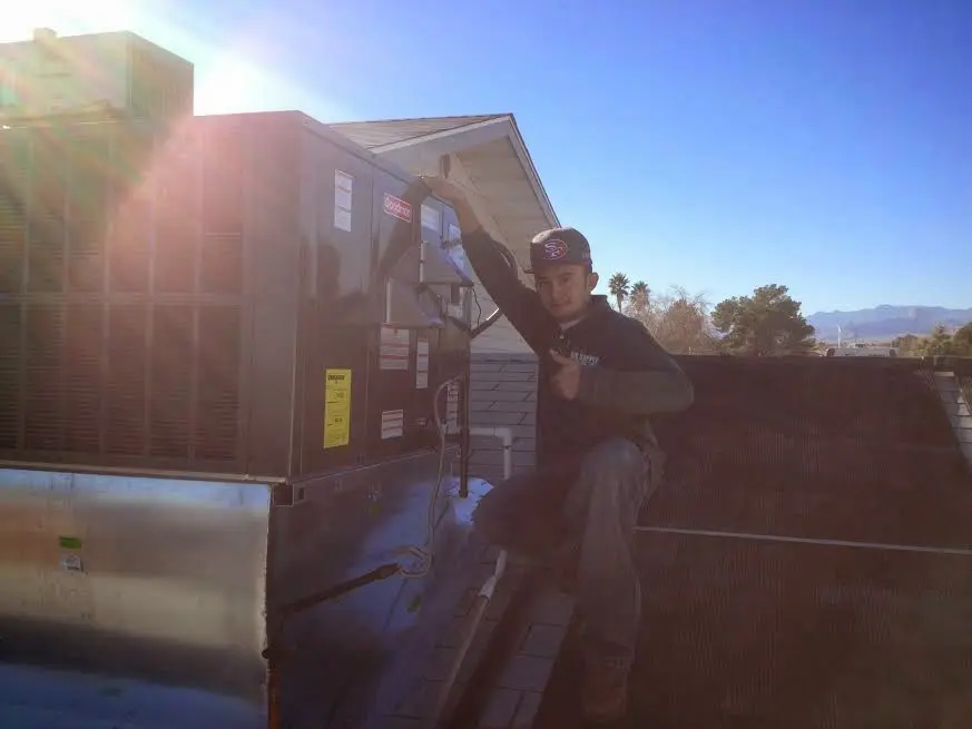 HVAC technician performing Heat Pump Repair on a rooftop unit in Angier