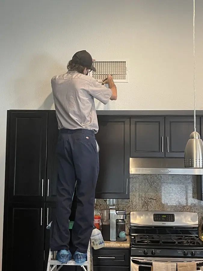 Technician inspecting an air vent during HVAC service in Angier